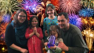woman, three girls, a man with fireworks in the background