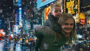 image of a girl giving a piggy back to a boy with image of NYC background